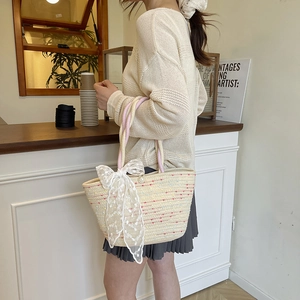 Chic woven beach tote with colorful stripes, lace bow, and pearl accent in a cozy cafe