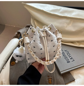 Détail du sac seau plissé blanc avec imprimés nœuds noirs et breloque pompon doux