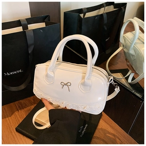 Details einer weißen Lackleder-Handtasche mit Schleifendekor und Spitzenbesatz