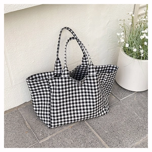 Detail of black and white checkered canvas tote bag with textured fabric and soft handles