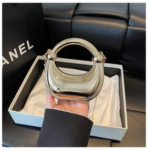 Detailed view of mini golden crescent handbag with metallic finish and chain strap