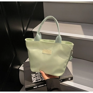 Detail der hellgrünen wasserdichten Nylon-Handtasche mit Fashion-Label und Reißverschluss