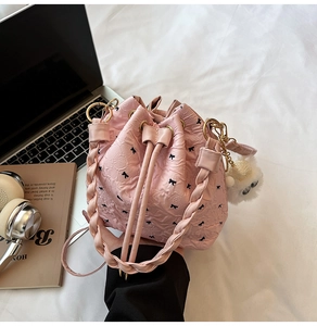 Détail d'un sac seau rose avec motif nœud, breloque en peluche blanche et anneaux en métal