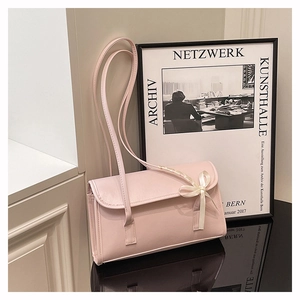 Détail du sac baguette rose clair avec un nœud en soie sur fond artistique moderne
