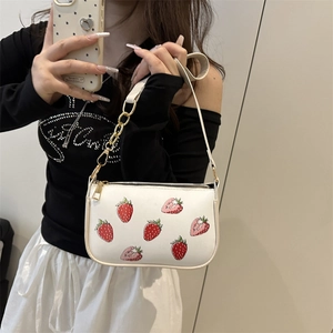 Sac à bandoulière blanc avec imprimé fraise et chaîne métallique tenu par un modèle