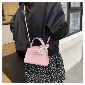 Detail of pink croc-embossed small square bag with silk scarf handle and metal lock