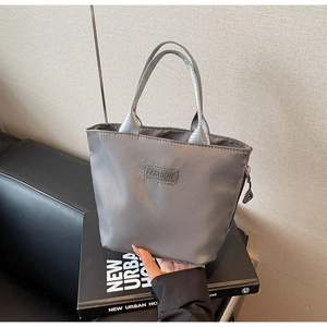 Detail der grauen, wasserabweisenden Nylon-Handtasche mit Reißverschluss und Logo