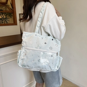Light blue plaid canvas tote bag with stars and transparent PVC pocket shown on shoulder