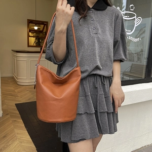 Minimalist orange-brown leather bucket tote bag with silver chain charm detail