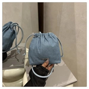 Dettaglio della borsa a secchiello in denim azzurro con coulisse e logo in metallo