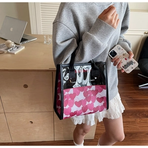 Dettaglio di una borsa tote in tela a cuori rosa e PVC nero tenuta da una modella