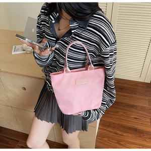 Detailansicht der rosa wasserfesten Nylon-Handtasche, gehalten von einem Modell