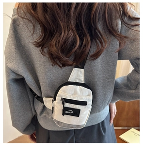 Detail of white nylon chest bag with black zipper and mesh base on a model back