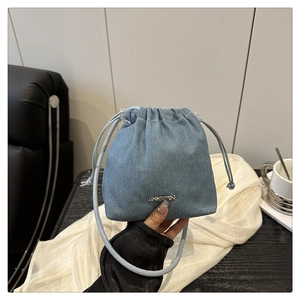 Dettaglio della borsa a secchiello in denim azzurro con coulisse e placca in metallo