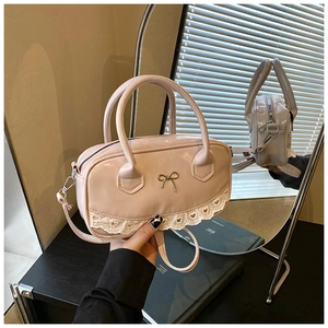 Detail der rosafarbenen Lacktasche mit Metallschleife und weißer Spitzenverzierung