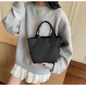 Detailansicht der schwarzen Nylon-Handtasche mit Fashion-Etikett getragen zum Freizeitoutfit