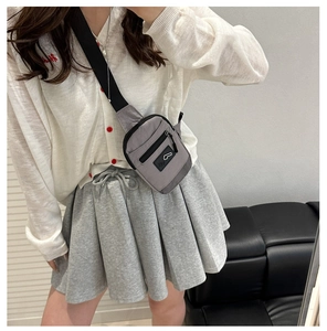 Detail of grey nylon crossbody bag with black zipper and adjustable shoulder strap