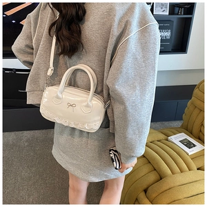 Detailansicht der weißen Lackleder-Tasche mit Spitze und Schleifen-Applikation