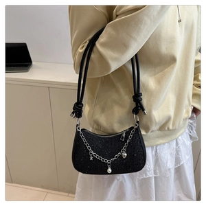 Détail d'un sac à bandoulière à paillettes noires avec breloques argentées et nœuds de corde