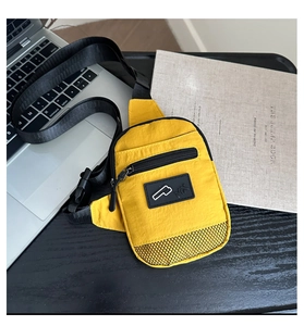 Detailed macro view of vibrant yellow nylon crossbody bag with MX logo on black surface