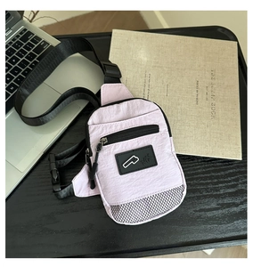 Detail of pink nylon crossbody bag with zipper pockets and mesh texture on a desk