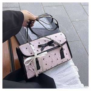 Detail of pink ruffled texture handbag with black bow patterns and long white ribbon accent