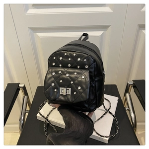Détail d'un sac à dos noir matelassé avec clous argentés et fermoir rotatif en métal