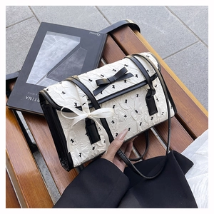 Detail shot of beige wrinkled fabric bag with black bird embroidery and ribbon