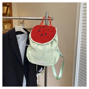 Détail du sac à dos pastèque vert avec imprimé de fruits et broderie suspendu sur un support