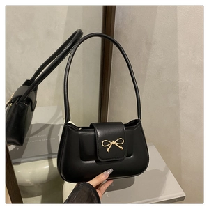 Détail de la boucle élégante en forme de nœud doré sur le sac baguette en cuir noir mat