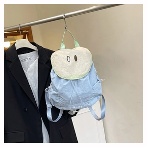 Détail du sac à dos bleu clair avec rabat crème brodé et logo Pear au style fruité