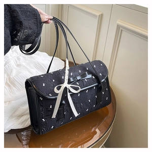 Detail of black quilted shoulder bag with white rabbit patterns and elegant bow decoration