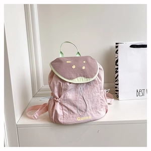 Détail macro du sac à dos en nylon rose avec poignée verte et broderie Guava