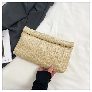 Macro shot of beige straw envelope clutch bag with golden ring detail on white fabric