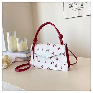 Détail d'un sac à bandoulière blanc avec imprimé cerise rouge et poignée à nœud élégant