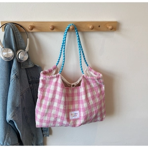 Dettaglio della borsa tote in tela a quadretti rosa con manici intrecciati ed etichetta