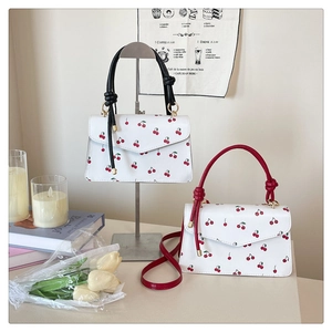 Détail du mini sac à main blanc à motif cerise avec poignée nouée et bandoulière