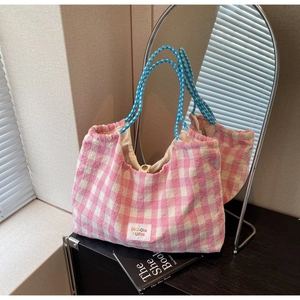 Close-up of pink plaid tote bag featuring thick tweed texture and woven rope handle