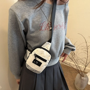 White nylon crossbody fanny pack with black zipper pocket and logo on model in soft light