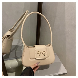 Détail du sac baguette crème élégant avec boucle en nœud métallique et cuir lisse poli