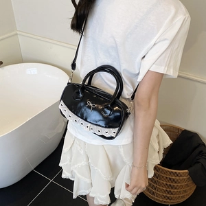 Minimalistische schwarze Lackleder-Tasche mit Metallschleife und weißer Spitze
