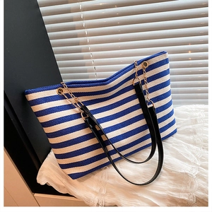 Detail of blue and white striped canvas tote bag with gold metal chain straps