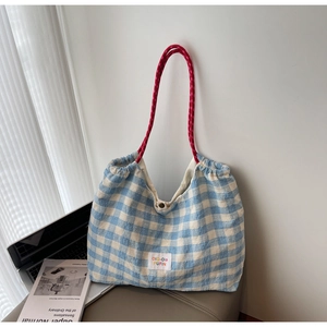Detail of blue and white checkered tote bag with dual-tone red woven rope handle