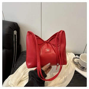 Detail of red faux leather shoulder bag with drawstring knot and logo plaque
