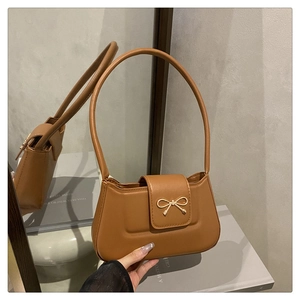 Détail macro d'un sac en cuir PU caramel avec boucle décorative en forme de nœud doré