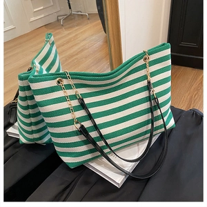 Detail of green and white striped canvas tote bag with gold chain and leather strap