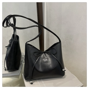 Close-up of black leather shoulder bag with drawstring bow and silver metal beads