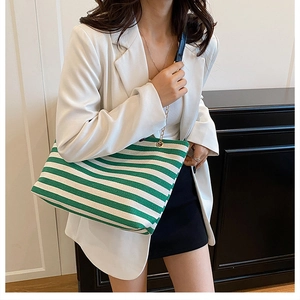 Close-up of green and white striped tote bag with leather handles and chain detail