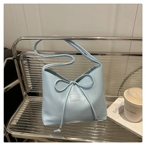 Close-up of light blue leather handbag with bow drawstring and silver metal beads