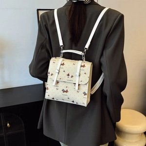 Mini cream backpack with brown dachshund prints and white straps worn by model